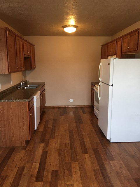 A kitchen with wooden floors and white appliances.