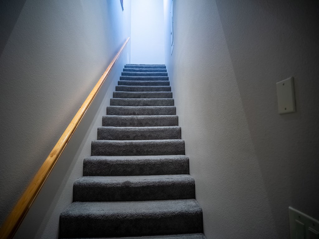 a flight of stairs leading up to a hallway with a light on the side