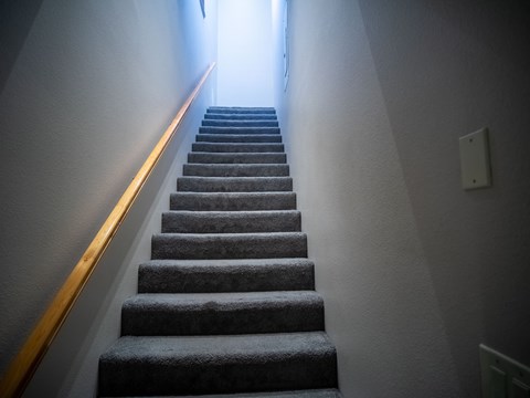 a flight of stairs leading up to a hallway with a light on the side