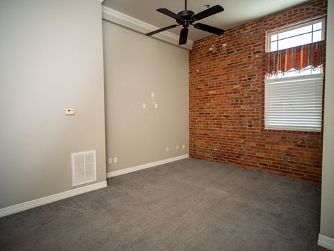 an empty room with a brick wall and a ceiling fan