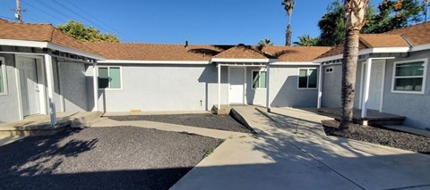 a white house with a sidewalk and palm trees