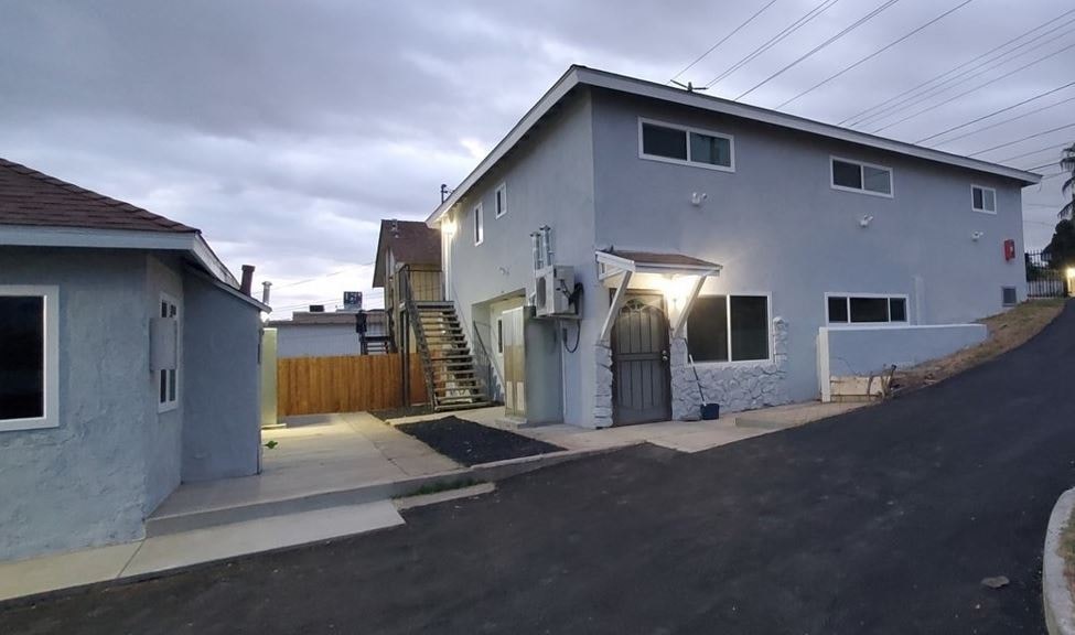 the front of a white house with a driveway and stairs