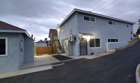 the front of a white house with a driveway and stairs