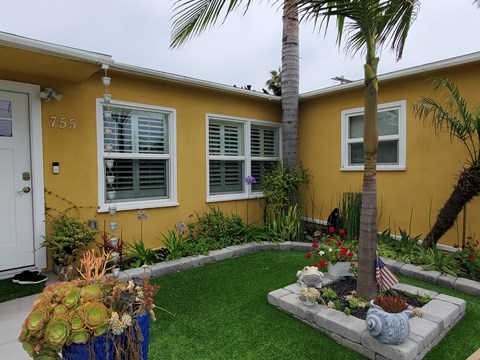 a yellow house with a yard and palm tree in front of it