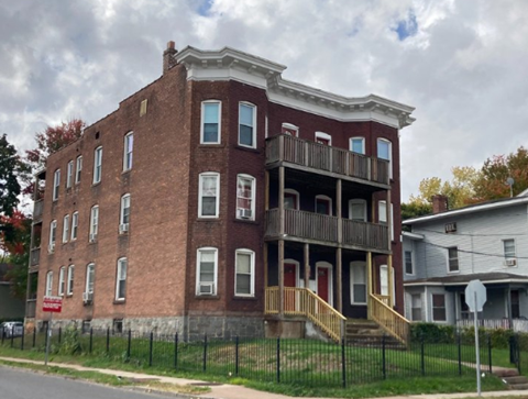 a red brick building with two balconies and a fence