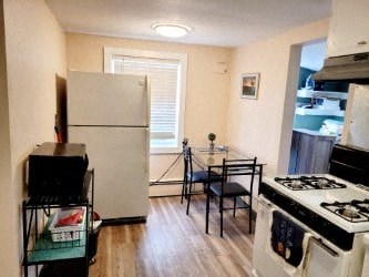 A kitchen with a white fridge, black stove, and a small table with two chairs.