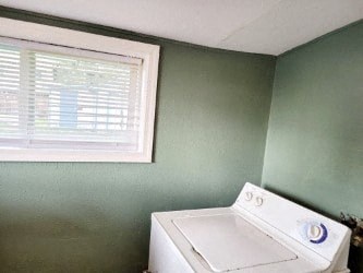 A white washing machine sits in a room with green walls.