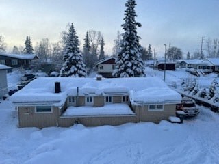 A house covered in snow with trees in the background.