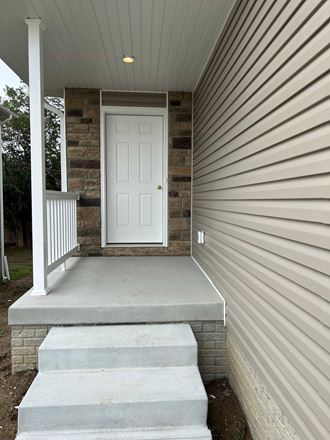 the front door of a home with steps and a porch