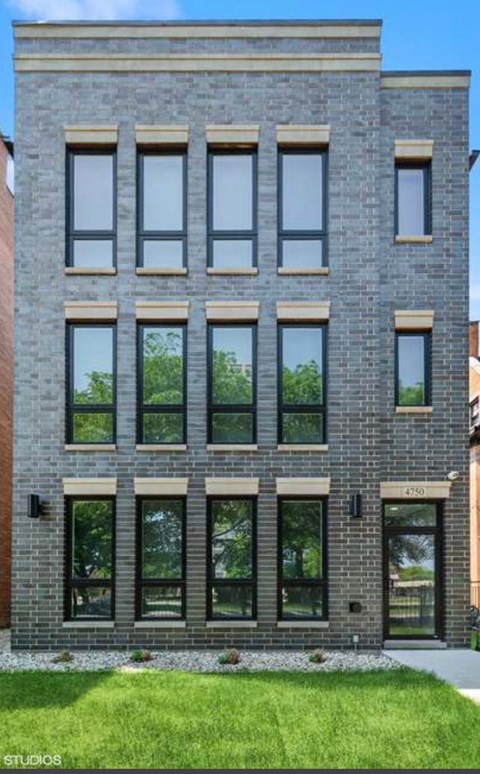 a brick building with windows and grass in front