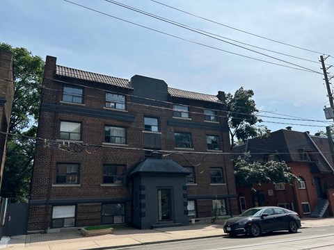 A black car is parked in front of a brick building.