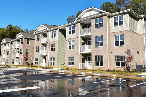 Apartment building with a parking lot in front.