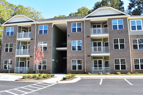 A large brick apartment building with a parking lot in front.