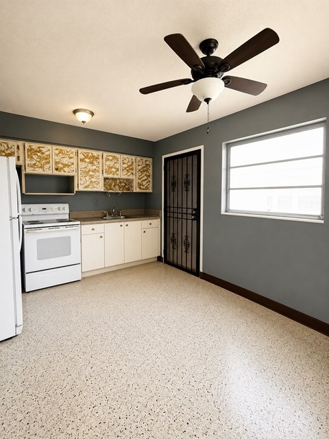 A kitchen with a white refrigerator and a ceiling fan.