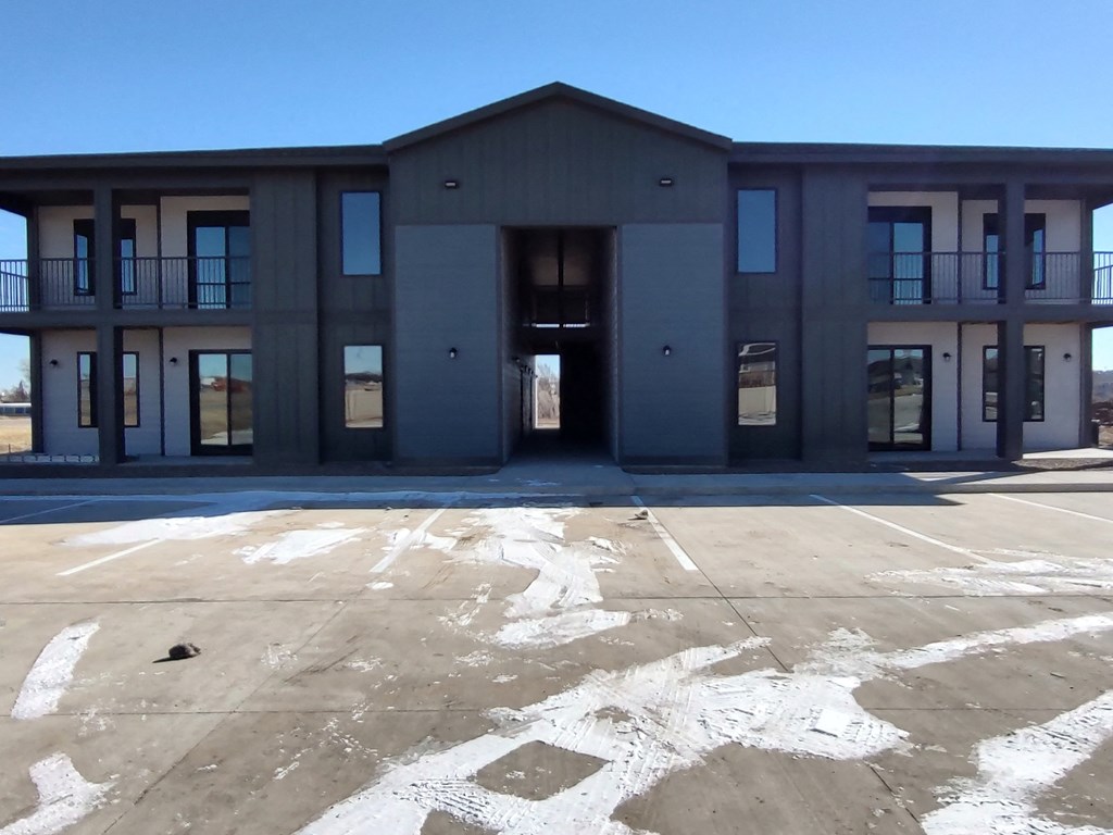 the front of a new building with a parking lot