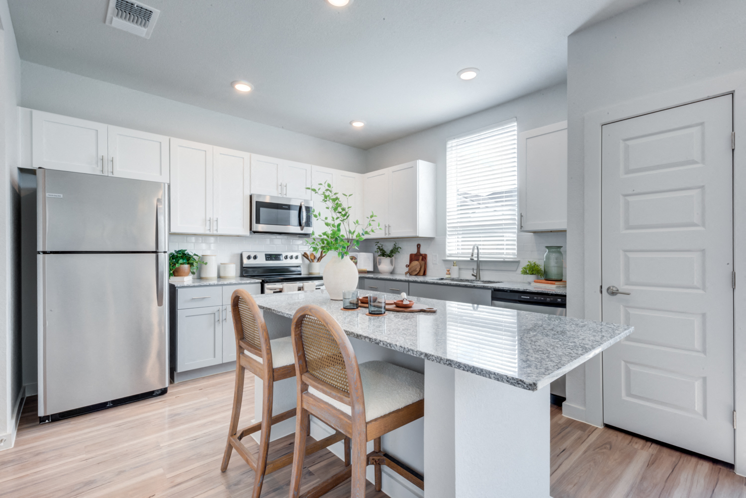 a kitchen with white cabinets and a marble counter top