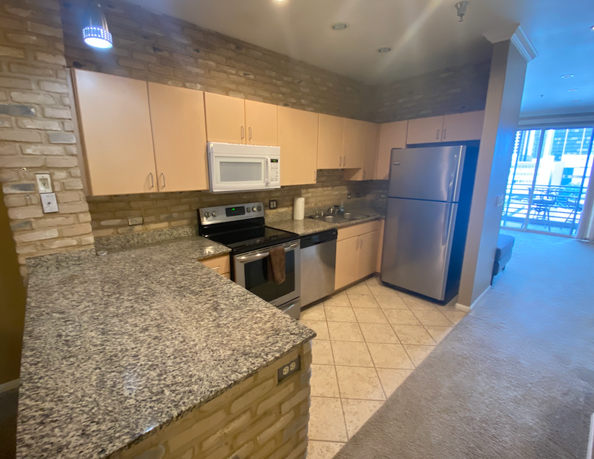 a kitchen with granite counter tops and a stainless steel refrigerator