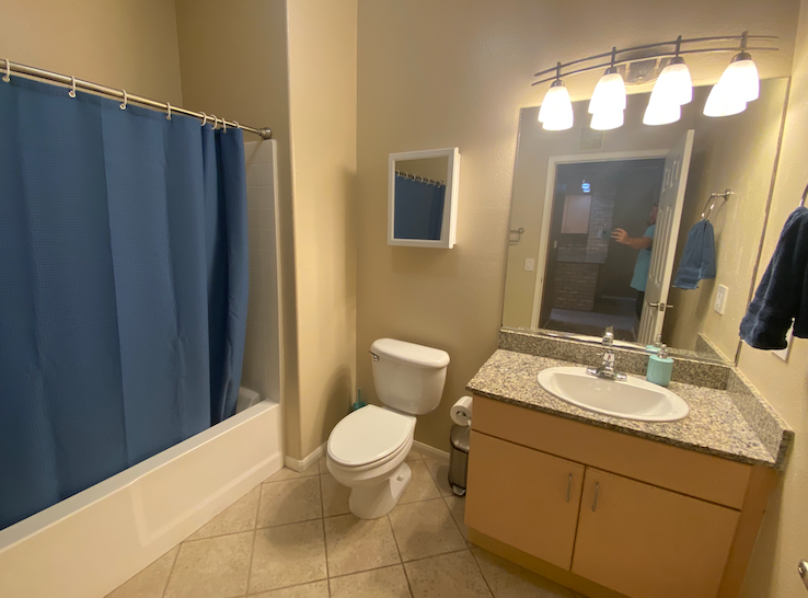 a bathroom with a blue shower curtain and a sink and a toilet