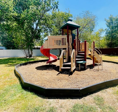 A playground with a red slide and a wooden play structure.