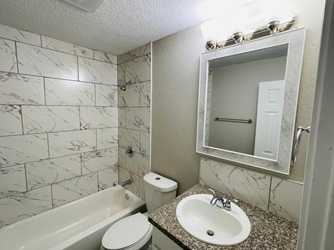A bathroom with a marble tile wall and a white toilet and sink.