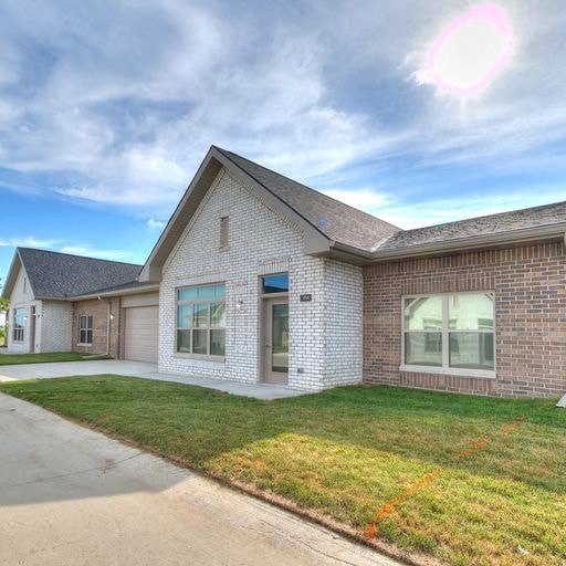 the front of a brick house with a lawn and a sidewalk