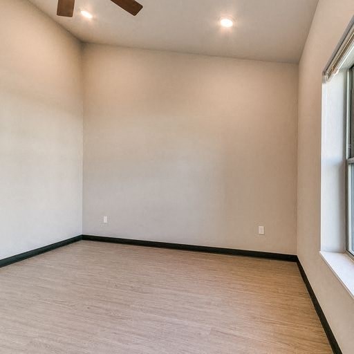 an empty room with two windows and a wood floor