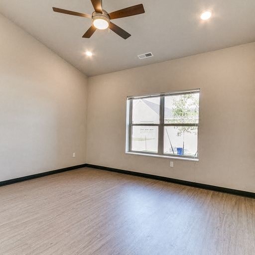 an empty living room with a ceiling fan and a window