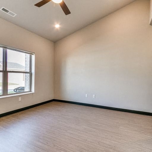 an empty room with a window and a ceiling fan