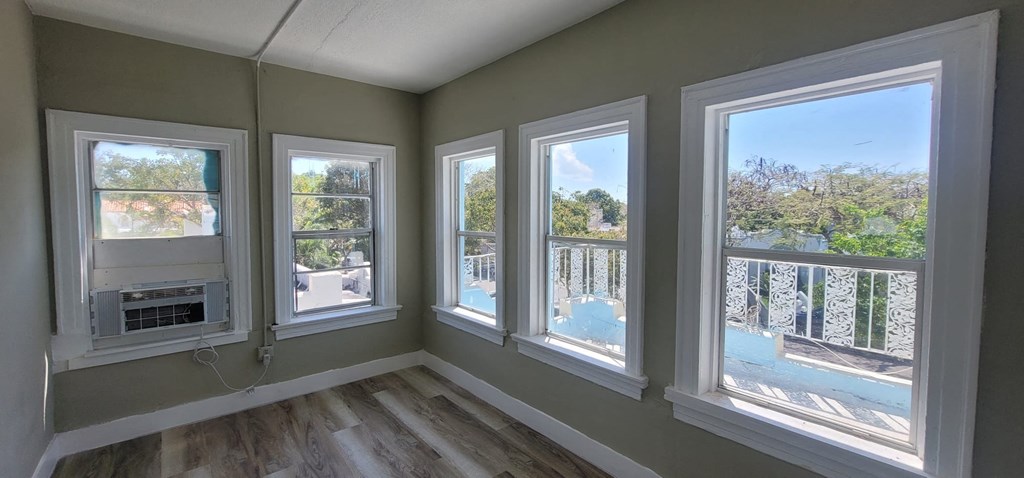 a living room with four windows and a wood floor