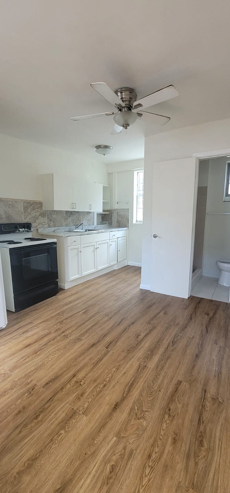 an empty kitchen with a ceiling fan and a wood floor