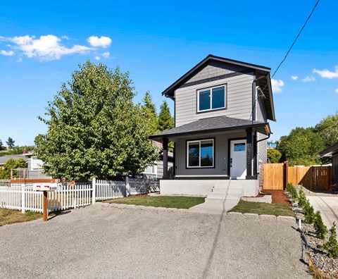 A house with a grey roof and a white picket fence.