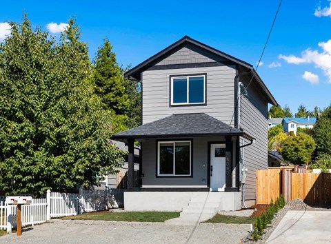 A grey house with a white fence in front.