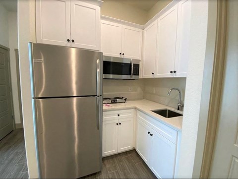 a kitchen with white cabinets and a stainless steel refrigerator