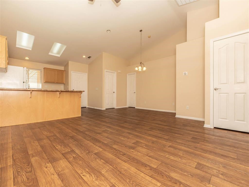 an empty living room and kitchen with wood floors