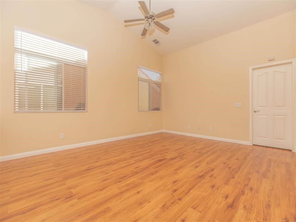 an empty living room with a ceiling fan and a door