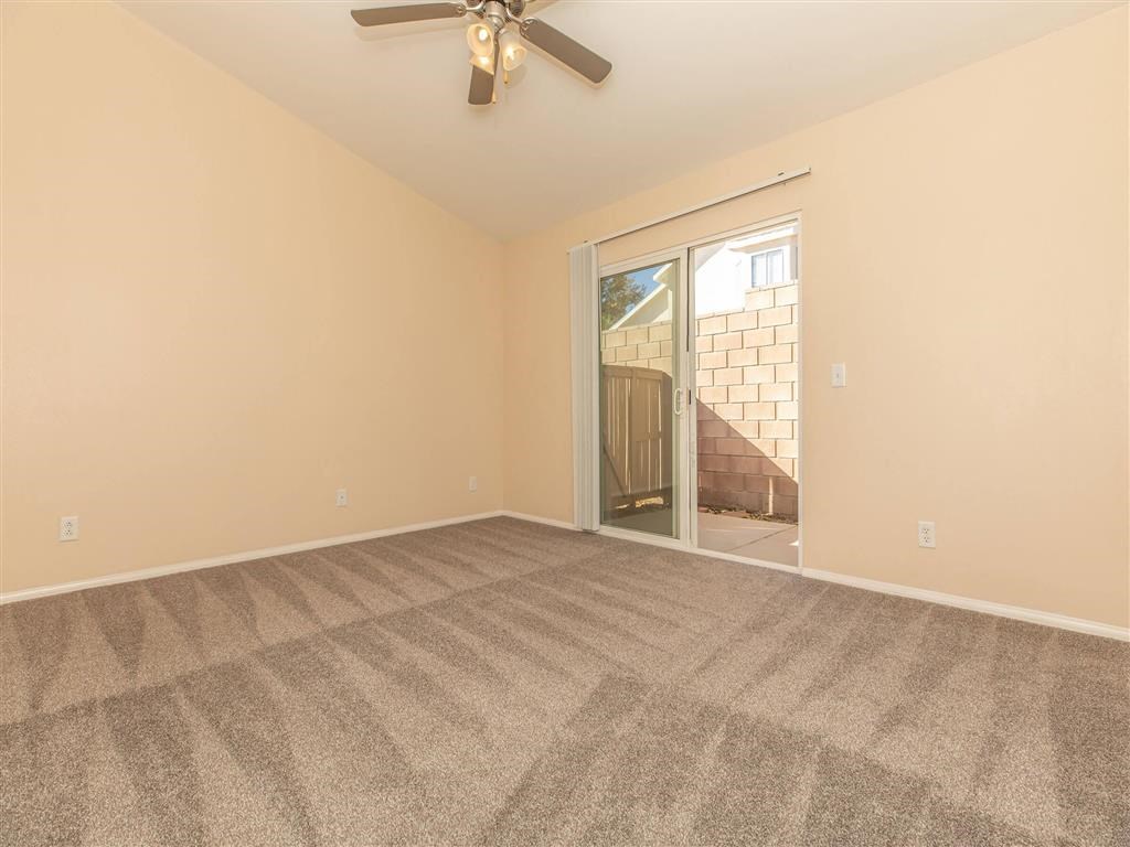 an empty living room with a ceiling fan and a sliding glass door