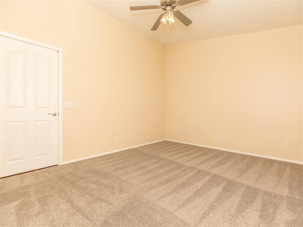 an empty living room with a ceiling fan and a door