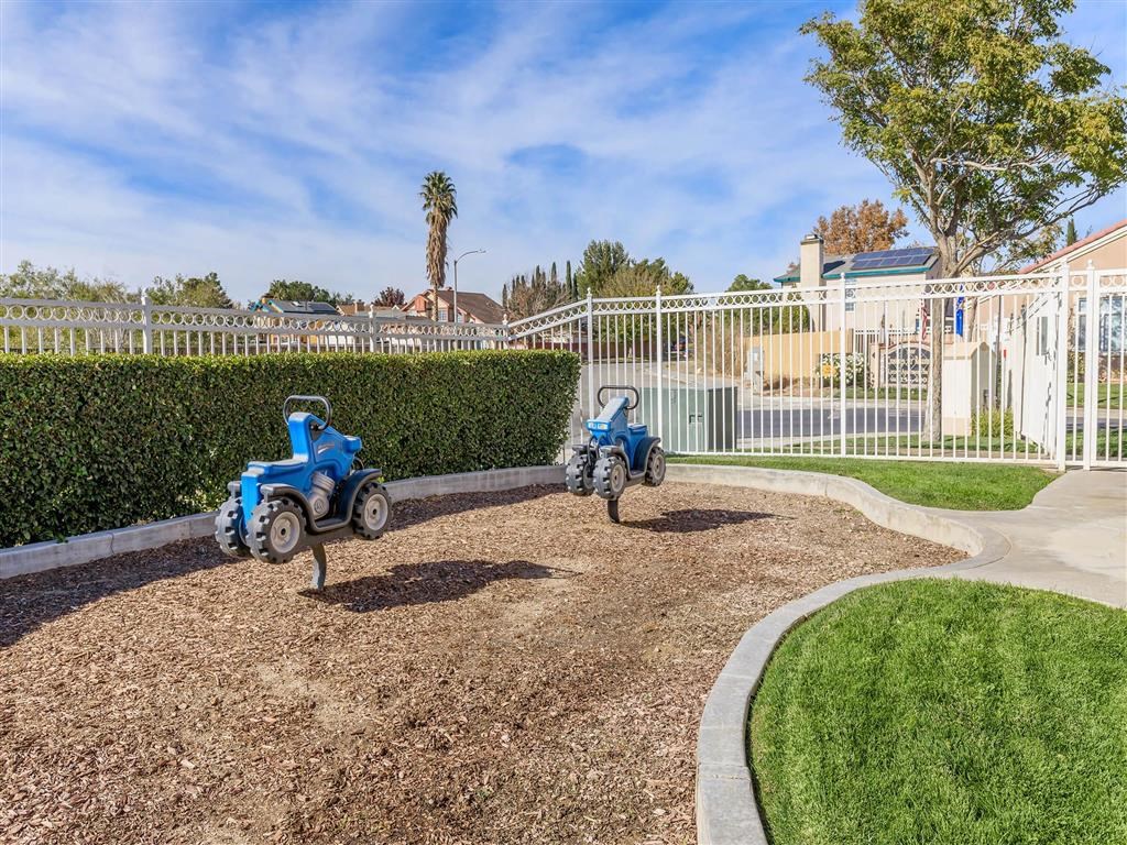 two toy cars in the mulch playground in front of a white fence