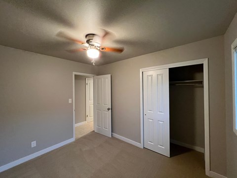 A room with a ceiling fan and three doors.
