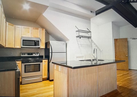 a kitchen with wooden cabinets and a black counter top