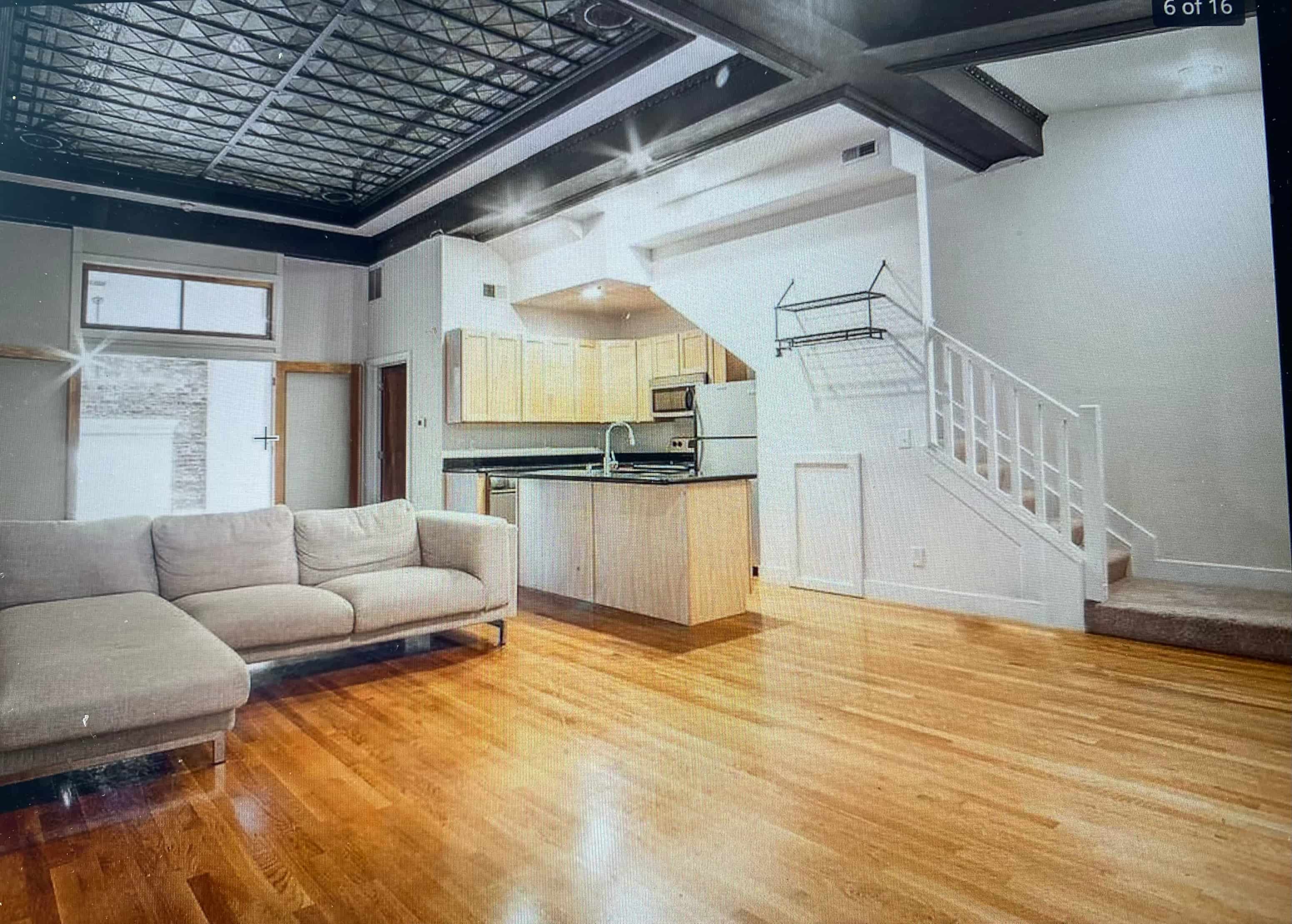 an empty living room with a couch and a kitchen