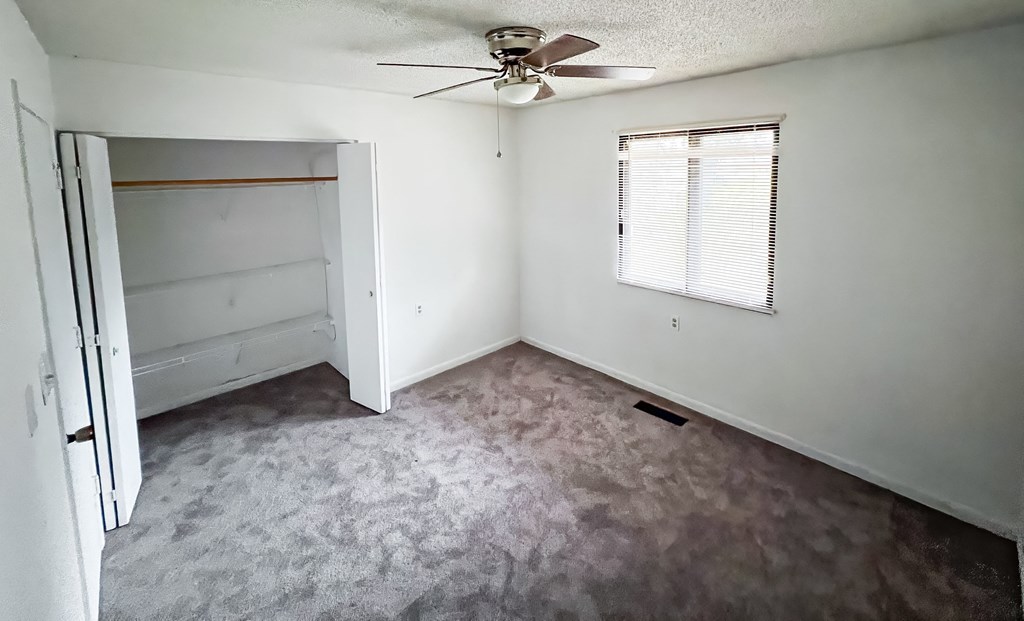 an empty room with a ceiling fan and a closet