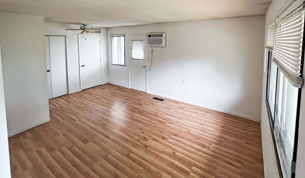 an empty living room with white walls and wood floors