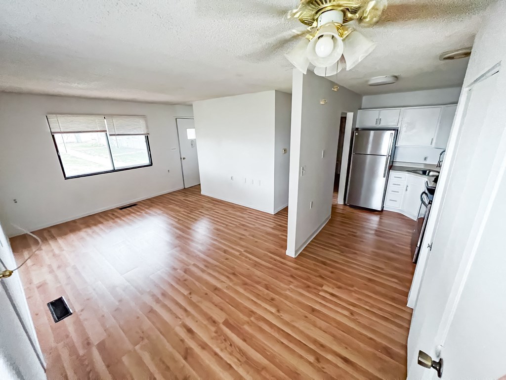 an empty living room and kitchen with wood floors