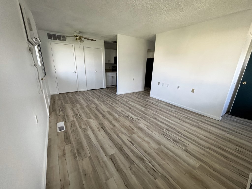 an empty living room with wood flooring and white walls