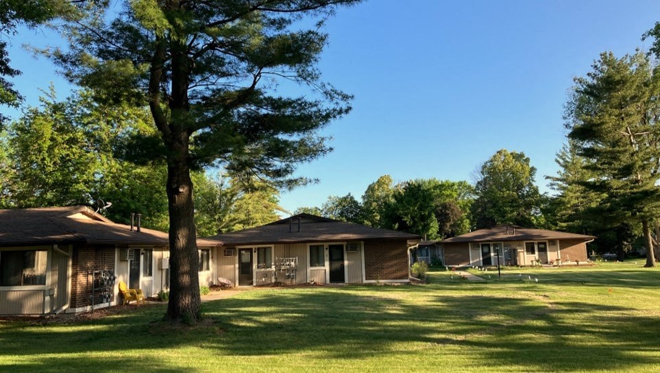 a group of houses in a grassy area with trees