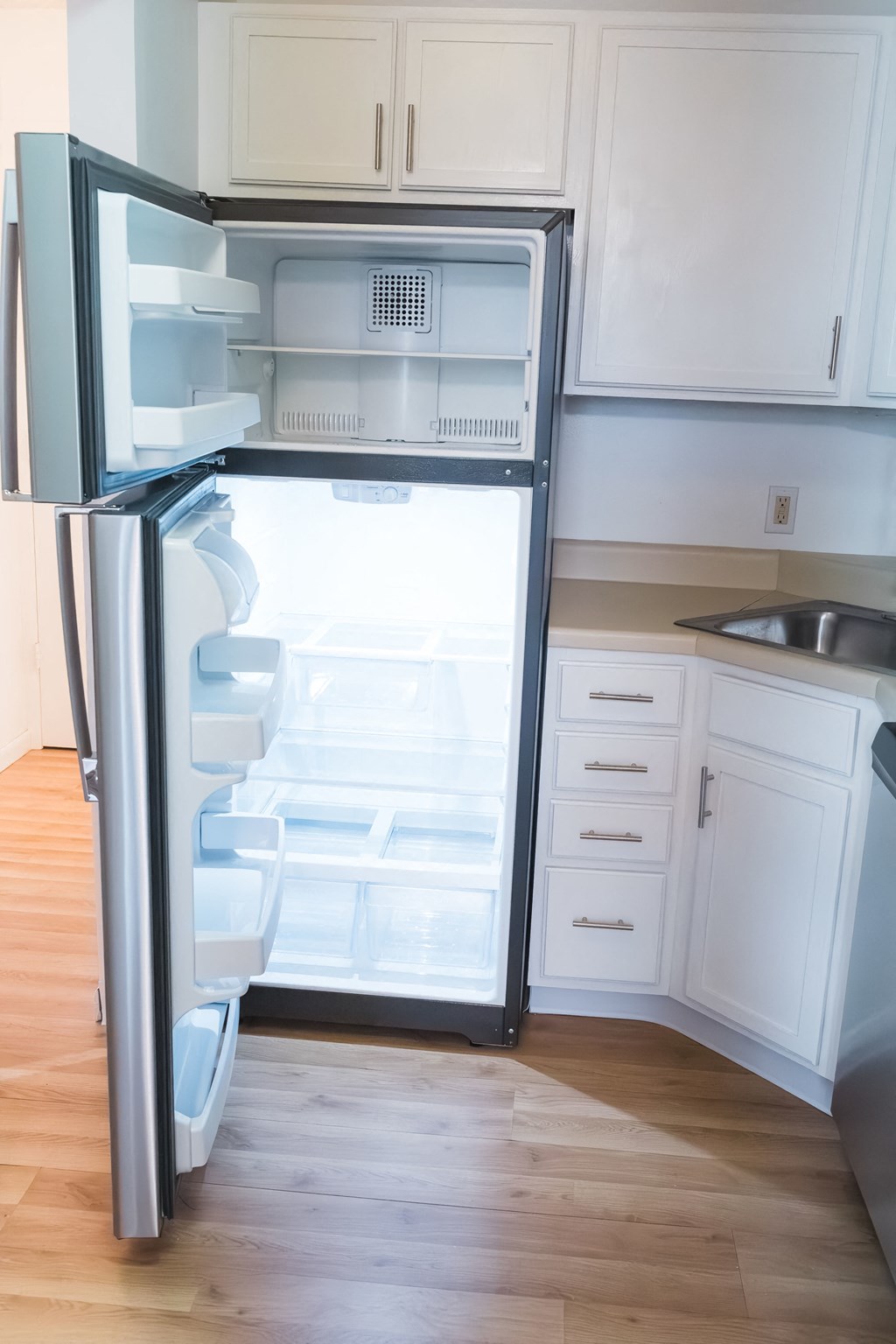 an empty refrigerator in a kitchen with white cabinets