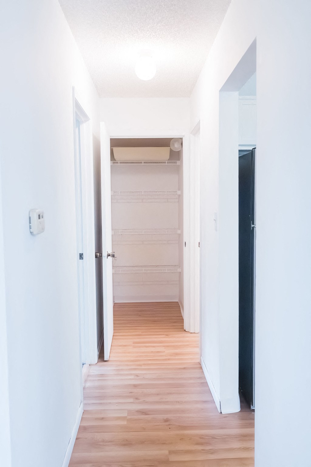 a hallway with wood floors and white walls and a closet