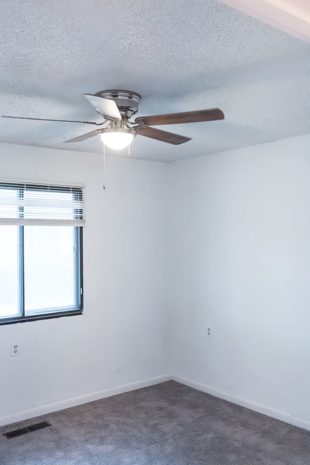 an empty room with a ceiling fan and a window