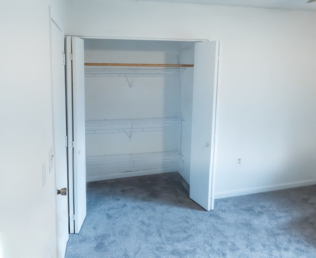 an empty closet in a room with white walls and carpet